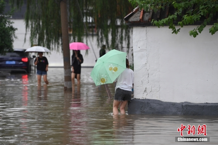 7月31日，市民行走在雨中的北京房山區(qū)瓦窯頭村。北京市氣象臺(tái)當(dāng)日10時(shí)發(fā)布分區(qū)域暴雨紅色預(yù)警信號(hào)。北京市水文總站發(fā)布洪水紅色預(yù)警，預(yù)計(jì)當(dāng)日12時(shí)至14時(shí)，房山區(qū)大石河流域?qū)⒊霈F(xiàn)紅色預(yù)警標(biāo)準(zhǔn)洪水。<a target='_blank' href='/'><p  align=