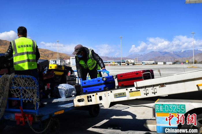 圖為機(jī)場工作人員傳送旅客行李箱?！≈芎?攝