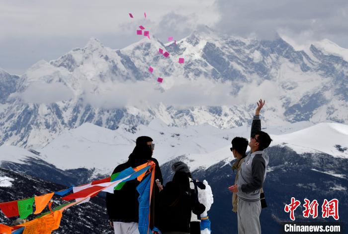 圖為5月14日，游客在西藏林芝色季拉山觀景臺(tái)拋灑“隆達(dá)”(風(fēng)馬旗，藏族民眾的一種祈福方式)?！±盍?攝