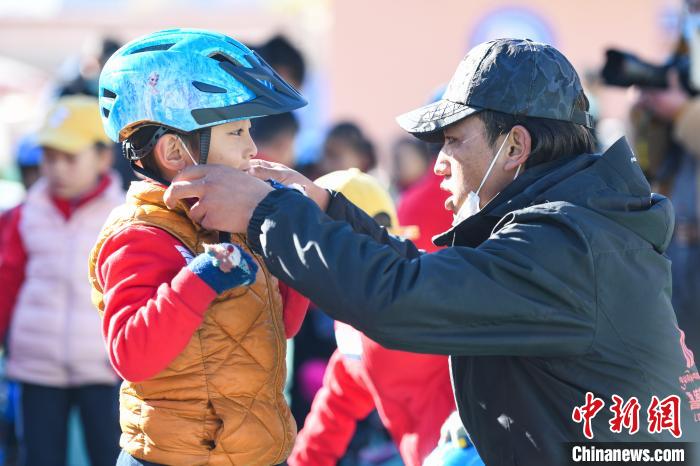 圖為拉薩市實(shí)驗(yàn)幼兒園孩子在教練的幫助下穿戴頭盔。　何蓬磊 攝