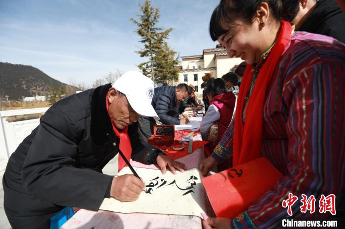 圖為林芝市文聯(lián)書法家協(xié)會(huì)會(huì)員向民眾贈(zèng)送藏文書法作品。　張力 攝